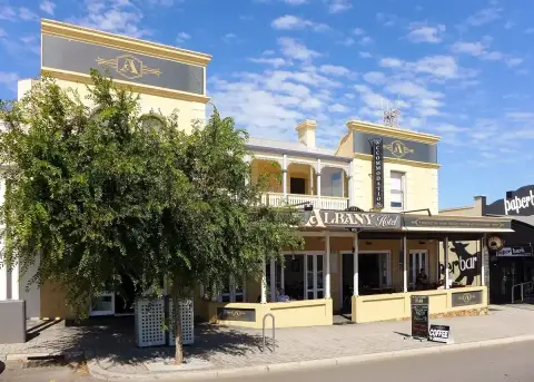 The same front seen past a street tree, tables under the verandah and a blackboard on the path