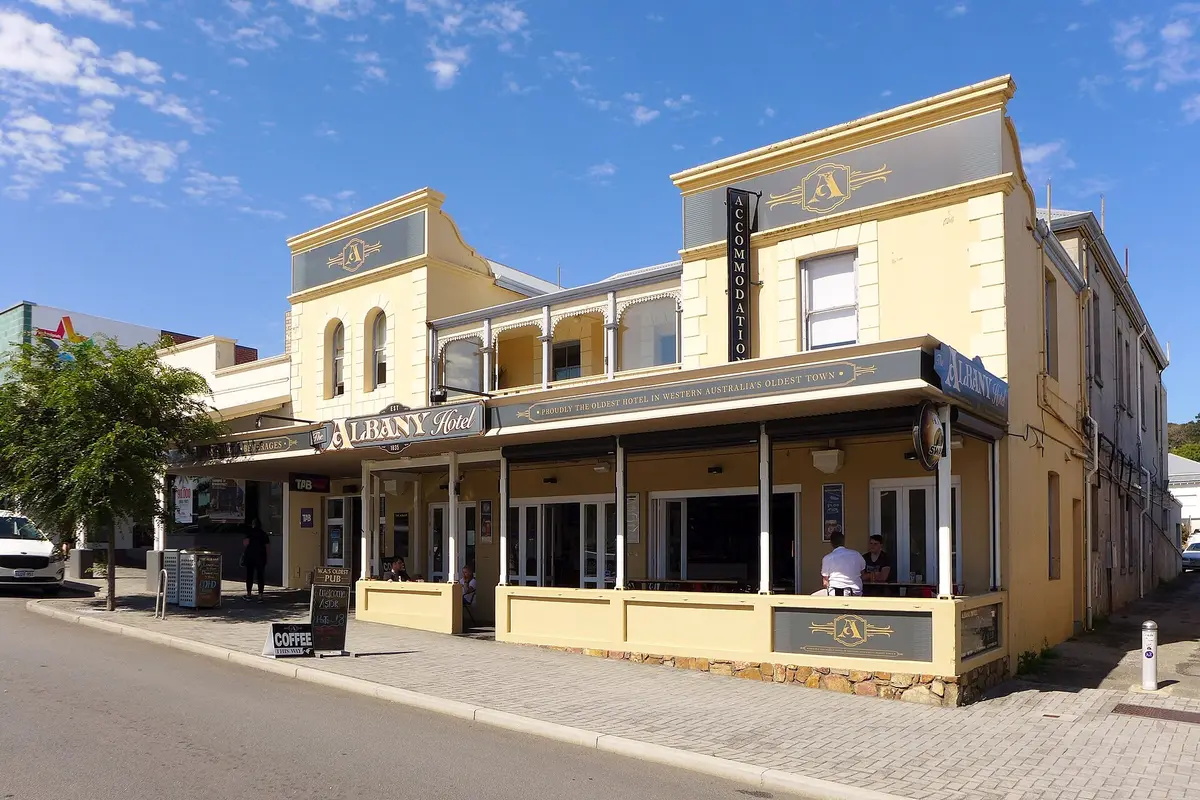 Two-storey cream hotel with an iron verandah and a sign reading The Albany Hotel over the footpath