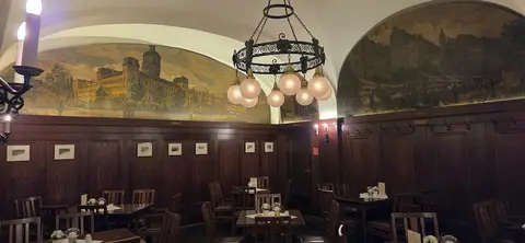 Panelled cellar room with painted views of old Leipzig above the panelling and tables laid for dinner