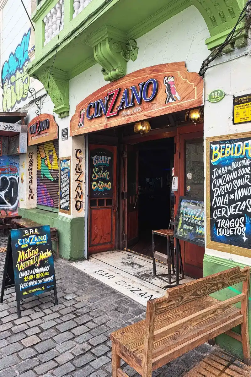 Doorway under a painted Cinzano desde 1896 board, chalkboards either side and a 1182 number plate