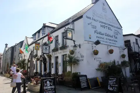 The same white inn in sunshine, hung with Welsh flags, lanterns and chalkboards along the street
