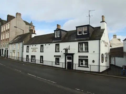 The long white front of the Black Bull, lettered Black Bull Hotel est 1568, behind the street railings