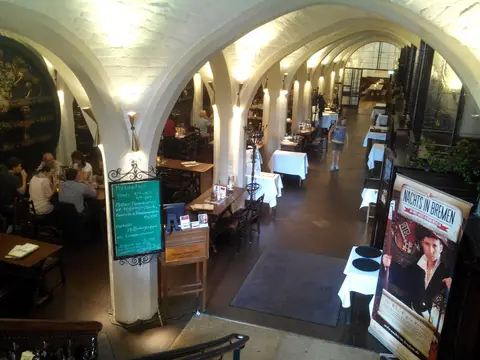 Whitewashed vaulted aisle with white-clothed tables between the piers, seen from a gallery