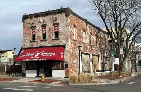 Brick corner saloon with a red awning lettered Buckhorn Exchange and antlers along the parapet
