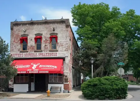The same brick corner in summer, red awning lettered Buckhorn Exchange, trees along the street