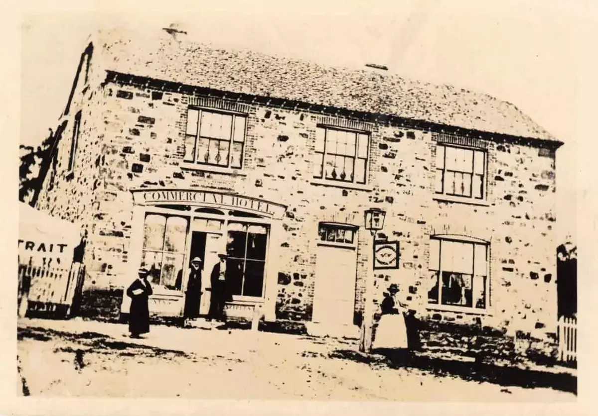 Early undated photograph of the two-storey rubble-stone Commercial Hotel at Collector, with figures standing in the dirt street