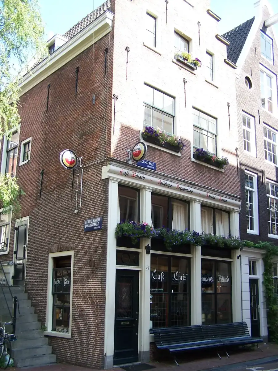 Brick corner house with Cafe Chris Anno 1624 painted across its windows and flower boxes at the sills