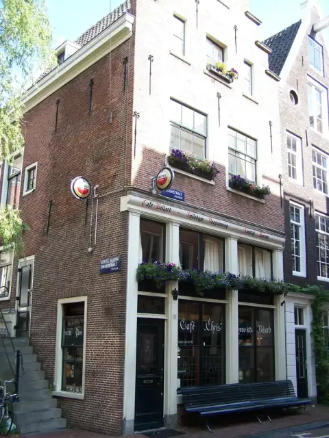 Brick corner house with Cafe Chris Anno 1624 painted across its windows and flower boxes at the sills