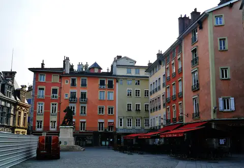 Place Saint-André from the other side, the café’s terrace and red awnings running along the pink and orange houses at right