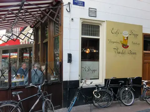 Brown cafe side wall with etched glass, a hand-painted beer advert and bicycles leaning outside