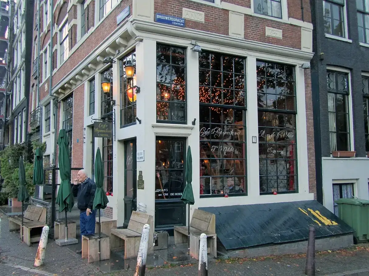 Corner café with small-paned windows and gold lettering reading Café 't Papeneiland, parasols outside