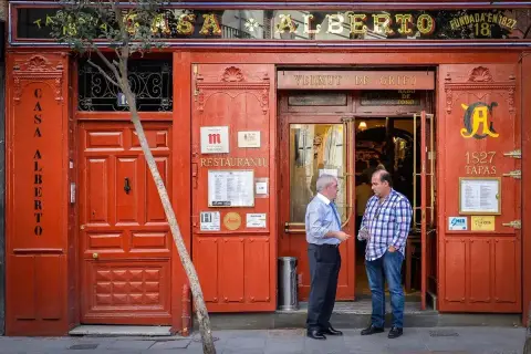 The same red front, its fascia reading Taberna Casa Alberto fundada en 1827, two men talking at the door