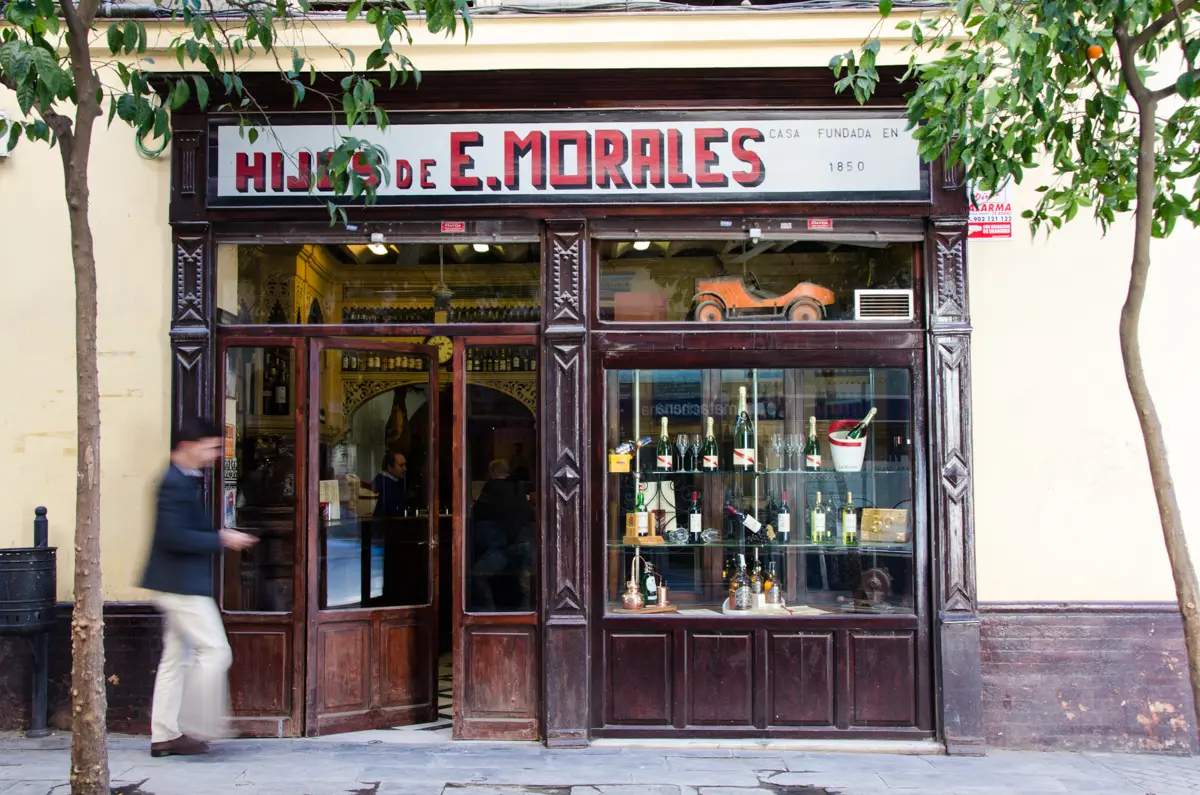 Dark wooden shopfront lettered Hijos de E. Morales, casa fundada en 1850, bottles in the window
