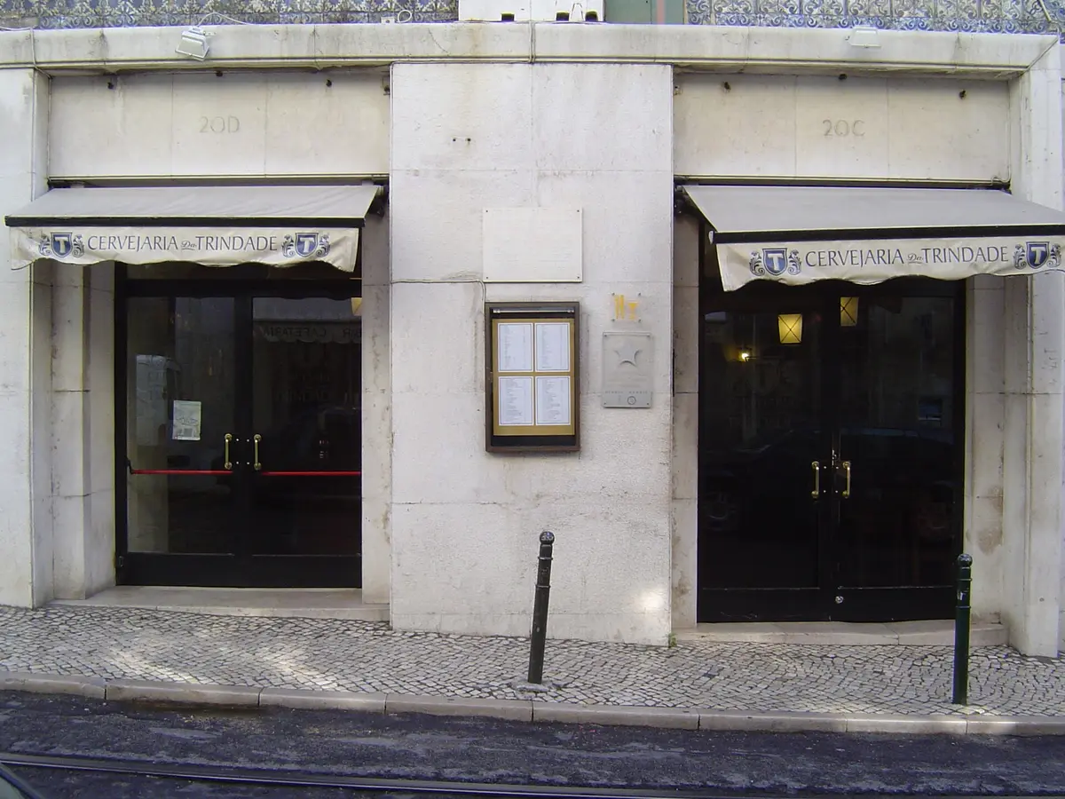 Stone shopfront at 20C and 20D with Cervejaria Trindade on two awnings and a menu case between