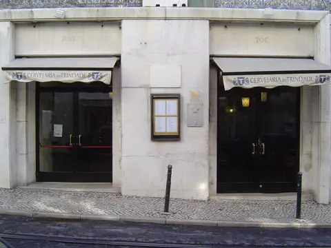 Stone shopfront at 20C and 20D with Cervejaria Trindade on two awnings and a menu case between