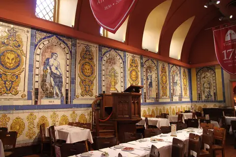 Tiled wall panels named Água, Vento and Fogo beside a carved wooden pulpit in the vaulted hall