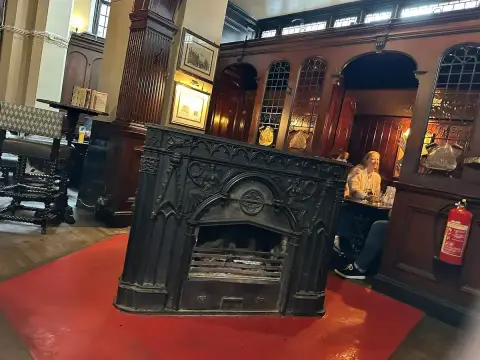 Free-standing cast-iron stove with a Gothic-arched front, facing rows of wooden drinking cubicles