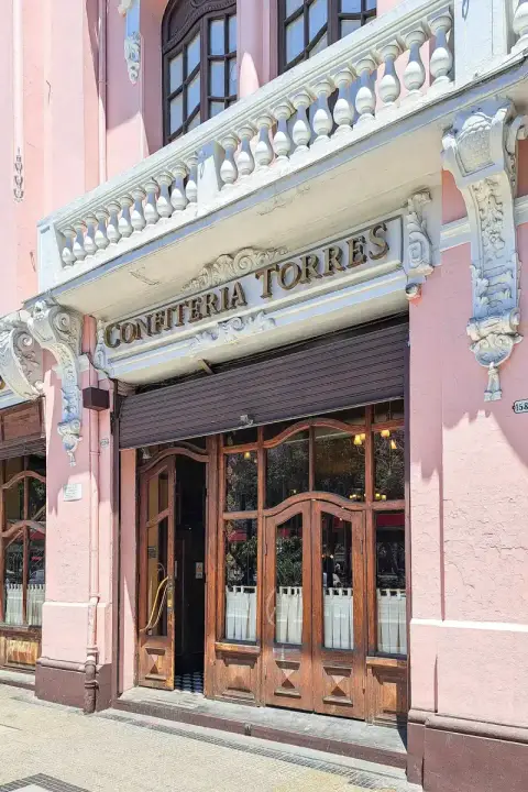 Confitería Torres in gilt letters over wooden double doors in a pink stucco front