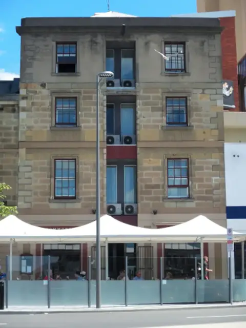 Part of the sandstone Morrison Street side of the Customs House Hotel, with a recessed central bay and white terrace awnings