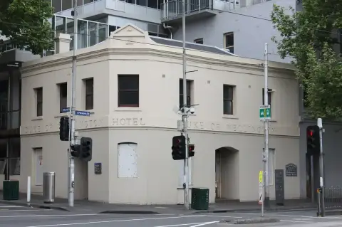 Cream rendered corner hotel with its name in raised letters below the parapet, at a city junction