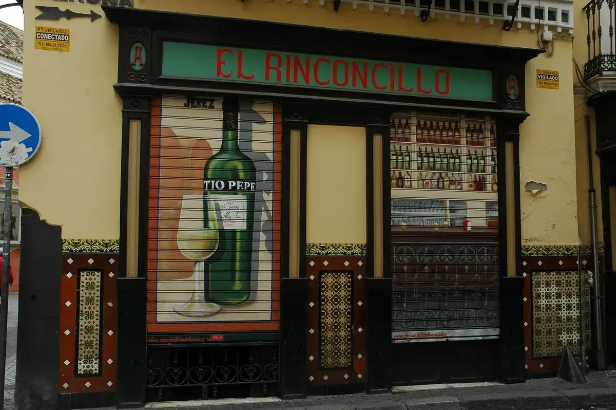 Tiled and timber tavern front with a green fascia in red lettering, shutters painted with sherry