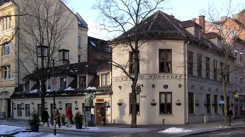 Corner of the café in winter with ENGEBRET cut into the wall and a bronze statue on the pavement