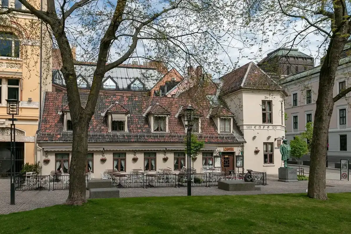 Low tiled-roof café on Bankplassen, its corner lettered anno 1857 Café, chairs out along the front