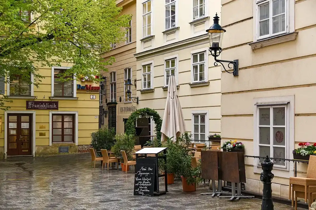 Narrow Vienna lane with an ivy-hung doorway lettered Esterházy, tables and chairs set outside it