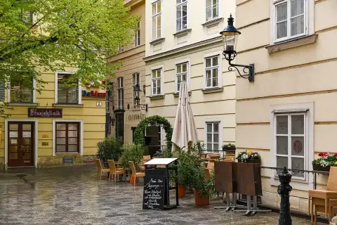Narrow Vienna lane with an ivy-hung doorway lettered Esterházy, tables and chairs set outside it