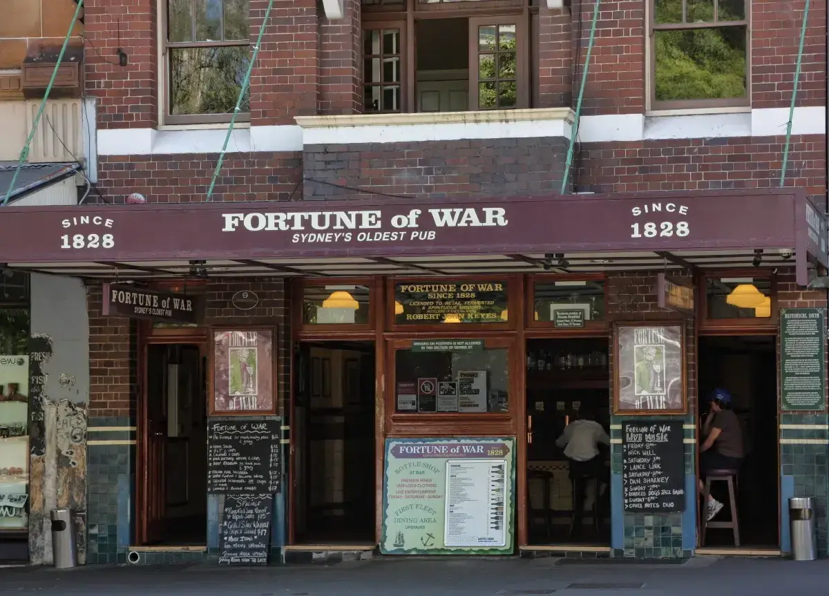 Brick pub front under a deep maroon awning lettered with its name, with open doors to the bar