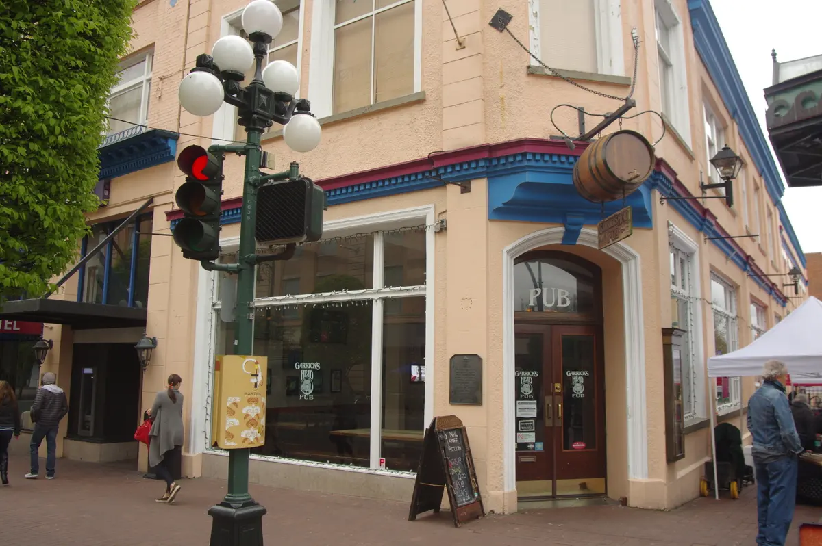 Corner entrance of the Garrick's Head on Bastion Square, a salmon-rendered building with blue cornice and a hanging barrel sign