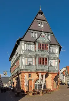 Tall half-timbered house with jettied upper floors, slate gable and a sandstone ground storey