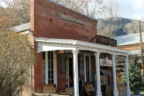 Brick saloon front painted Nevada's Oldest Thirst Parlor, with a covered porch and hanging sign