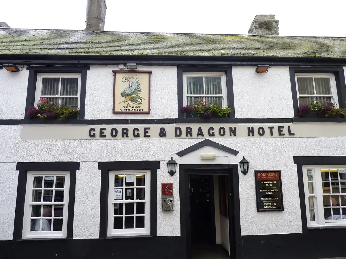 White and black painted inn front with a lettered fascia, sash windows and window boxes