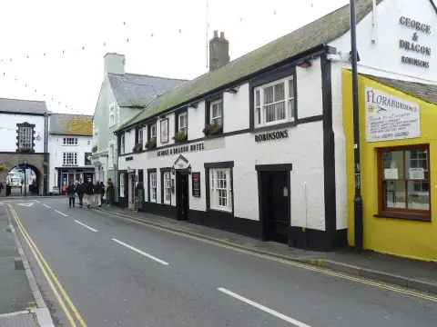 Long white inn running down a town street, with the town gate arch at the far end