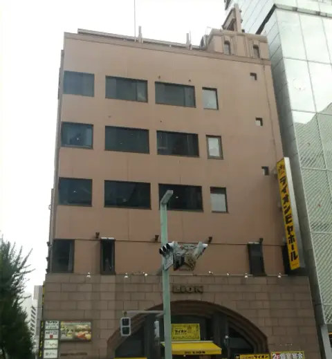 Brick-faced building with a carved lion over an arched entrance and a yellow Lion beer hall banner