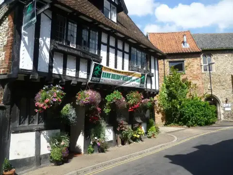 Close view of the jettied front hung with baskets of flowers and a beer festival banner