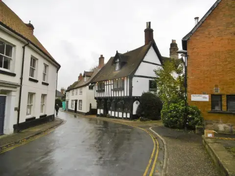 The timber-framed inn on a wet street corner opposite a red-brick arts centre