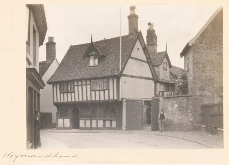 Black-and-white photograph of the jettied timber front of the Green Dragon in 1903, a man standing by the yard gates