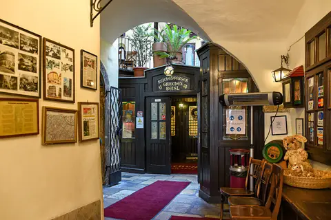 A dark panelled doorway down a vaulted passage, the name Griechen Beisl carved in gold above it