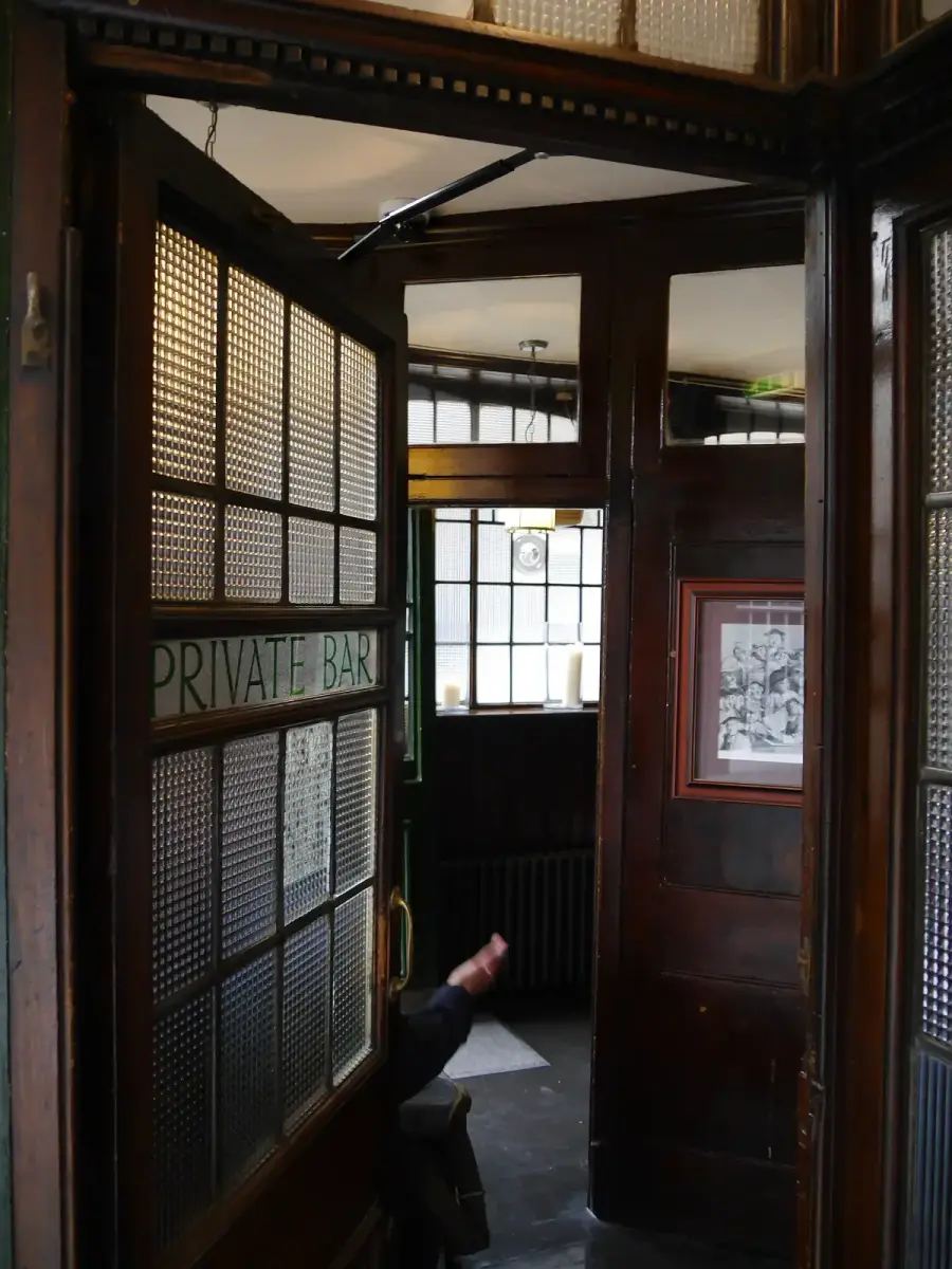 Dark mahogany screen and a glazed door lettered Private Bar, with obscured glass panels