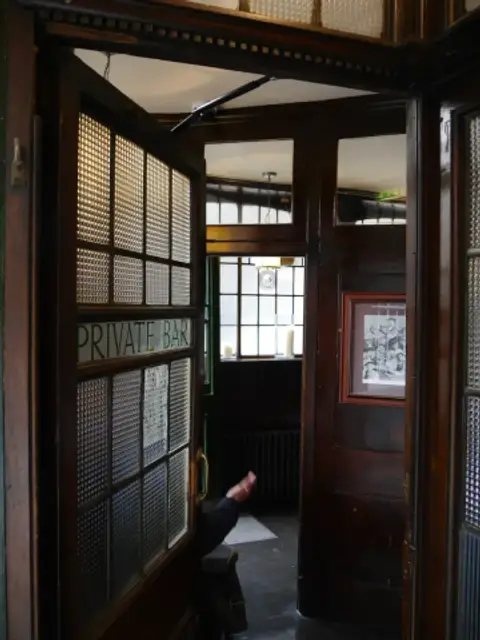 Dark mahogany screen and a glazed door lettered Private Bar, with obscured glass panels