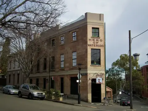 Three-storey sandstone corner hotel with its name carved in the wall and a painted hanging sign