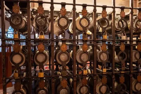 Iron racks of numbered pewter-lidded steins, each cage shut with its own brass padlock