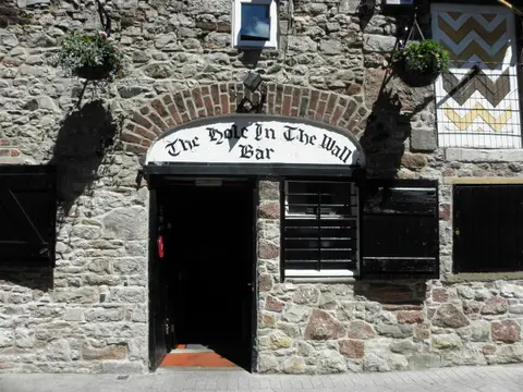 The stone front of the Hole in the Wall Bar, Armagh, its name painted on an arched board