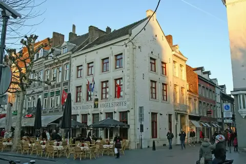 White gabled corner house on the Vrijthof lettered In den Ouden Vogelstruys, café tables in front