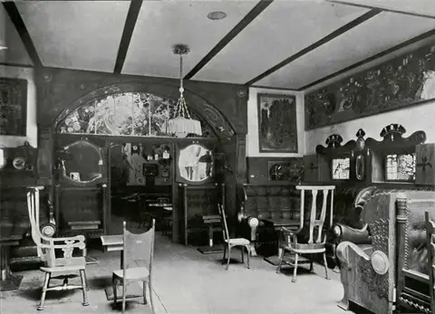 Café interior in 1911: an arched screen with stained glass, high-backed chairs and a panelled banquette