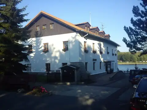 The same white inn in low sun, its long side lined with flower boxes above the water