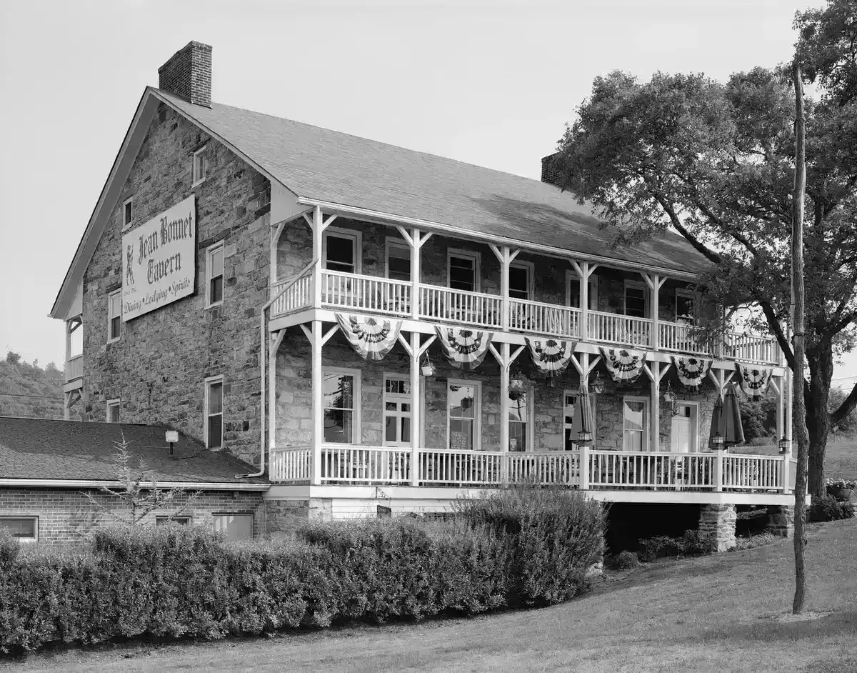 Two-storey fieldstone tavern with a white timber verandah on two levels and a painted sign