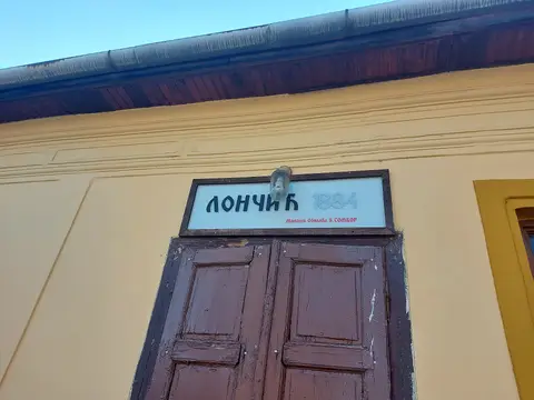 Painted board reading Лончић 1884 and the street address, fixed above the kafana’s brown doors